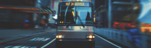 City bus with “Not in Service” sign driving through downtown at night.
