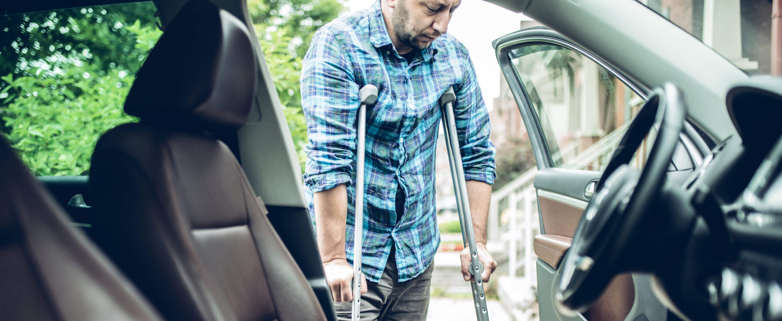 man using crutches is about to take the car. view from inside the car