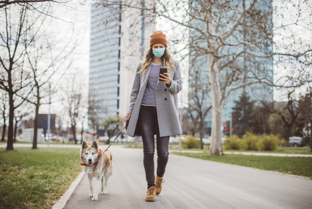 Woman walking her dog with a mask on.