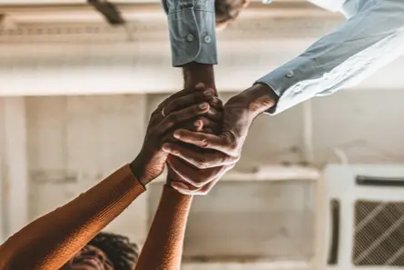 Two people helping each other up at work.