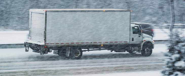 Commercial delivery truck driving through a snowstorm in Lake County