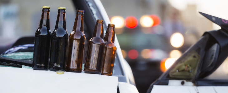 Alcohol bottles on hood of crashed car after drunk driving accident.