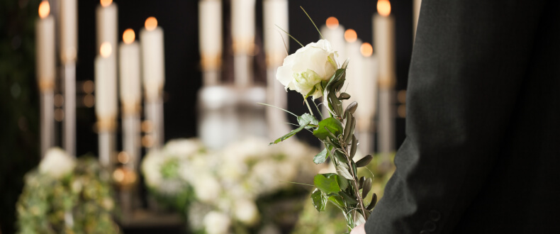Man holding white rose at a funeral